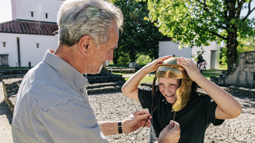 Grandpa and granson with Roman helmet in Cambodunum Archaeological Park