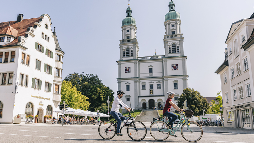 Two persons on their bikes in front of the Basilica of St Lorenz