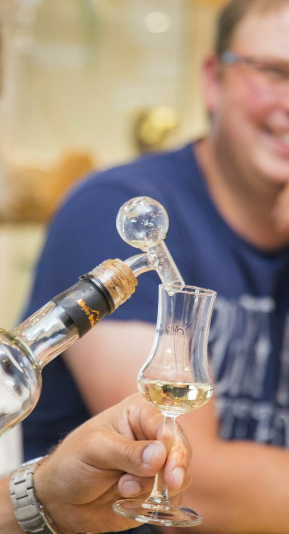 A man pours schnapps into a shot glass