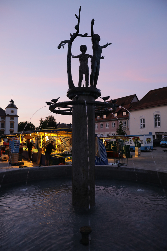 Der Hildegardbrunnen im Morgenlicht zu Beginn des Wochenmarktes