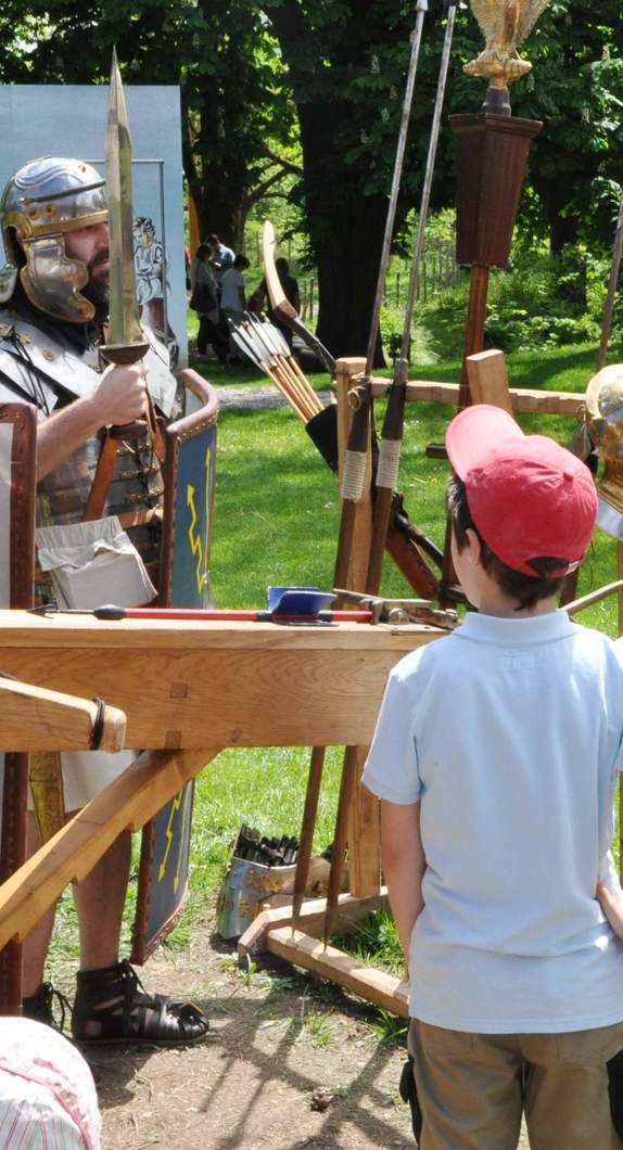 Römerdarsteller zeigt einen Jungen die Kampfausrüstung