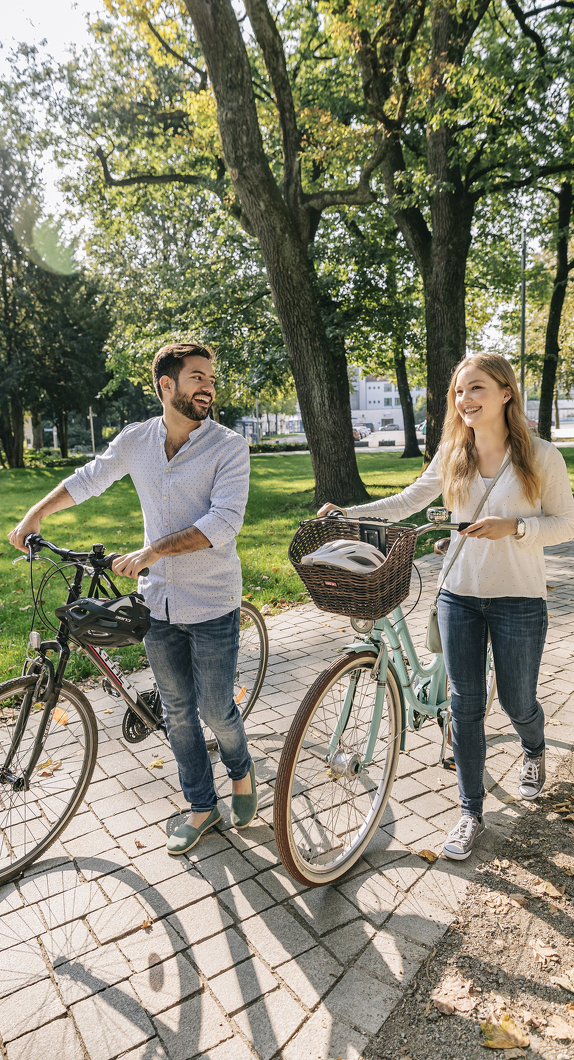 Zwei Radfahrer, die ihr Rad durch den Stadtpark in Kempten schieben