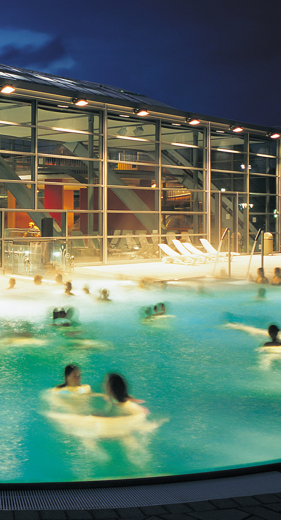 Beleuchtetes Außenbecken des  Erlebnis- und Freizeitbad Cambomare bei Nacht.