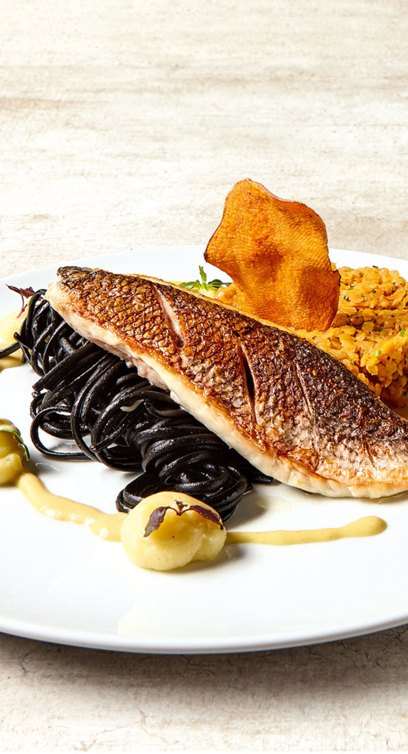 Doradenfilet angerichtet mit Linsenragout und schwarzen Nudeln