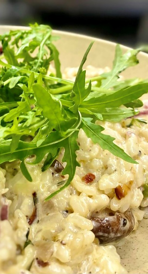 Pilzrisotto auf einem Teller garniert mit Rucola