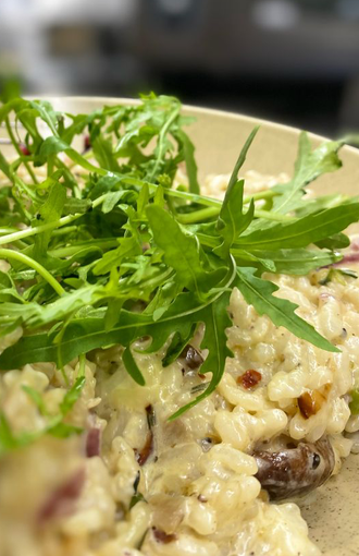 Pilzrisotto auf einem Teller garniert mit Rucola