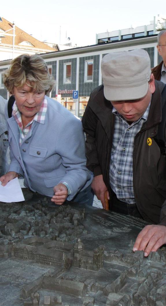 Stadtführerin mit sehbehindertem Mann am Stadtrelief