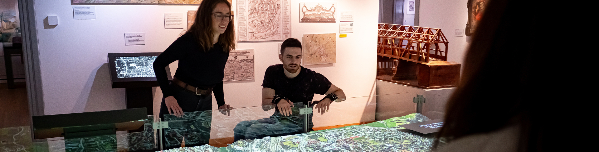Zwei Personen, eine davon im Rollstuhl, besichtigen das 3D-Stadtmodell im Kempten-Museum.
