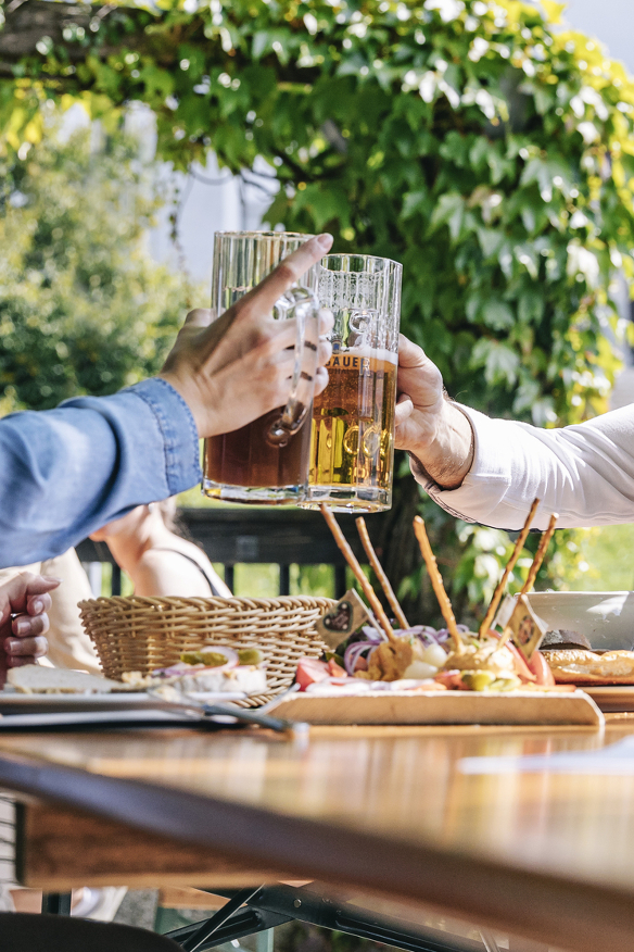 Zwei Freunde stoßen mit Bier im Biergarten an.