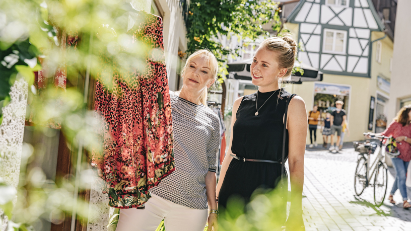 Mutter und Tochter schauen sich Kleidung vor einer Boutique an