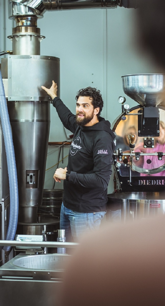 Ein Mann in der Kaffee-Manufaktur beim Erklären der Röstung