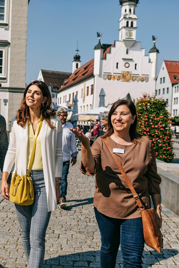 Eine Stadtführerin mit der Gruppe auf dem Rathausplatz