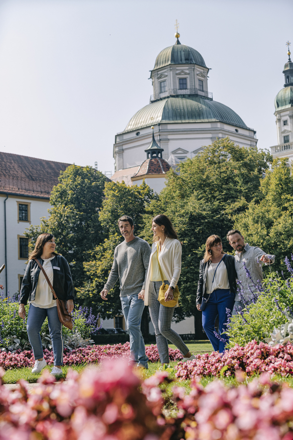 Stadtführung im Hofgarten Reisegruppe folgt Stadtführer durch eine bepflanzte Grünanlage